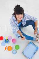 Happy woman sitting on floor with paint