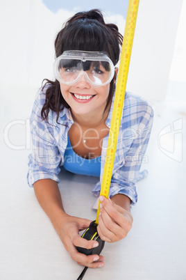 Happy woman lying on floor with measuring tape