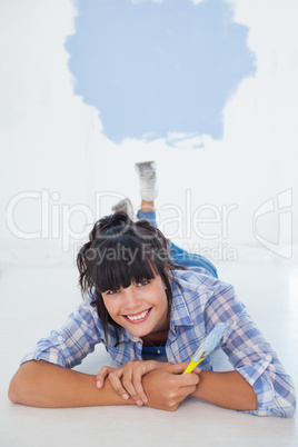 Attractive woman lying on floor holding paint brush