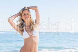 Beautiful blonde smiling and ruffling her hair in white bikini
