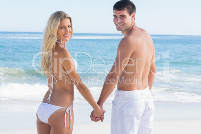 Rear view of couple holding hands looking at camera