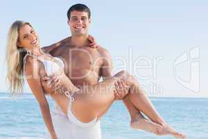 Man carrying his pretty girlfriend smiling at camera