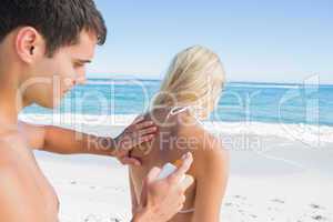 Man putting sun cream on girlfriends back
