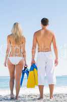 Couple holding flippers and looking at the sea