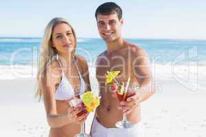 Beautiful young couple smiling at camera holding cocktails