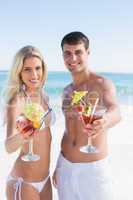Attractive young couple smiling at camera holding cocktails