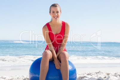 Fit young woman sitting on exercise ball smiling at camera