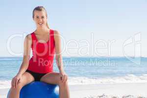 Athletic woman sitting on exercise ball looking at camera