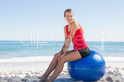 Athletic young woman sitting on exercise ball looking at camera