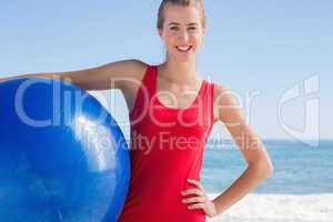 Fit blonde holding exercise ball looking at camera