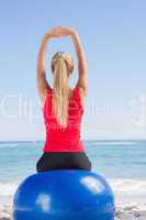 Fit blonde sitting on exercise ball looking at sea