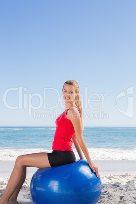 Smiling woman sitting on exercise ball looking at camera