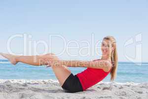 Fit blonde doing pilates core exercise smiling at camera