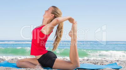 Athletic blonde stretching leg in yoga pose