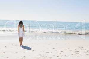 Brunette in white sun dress walking to the sea