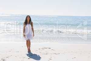Beautiful brunette in white sun dress walking from the ocean
