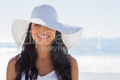Pretty brunette in white sunhat smiling at camera