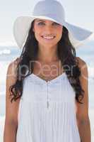 Happy brunette in white sunhat smiling at camera