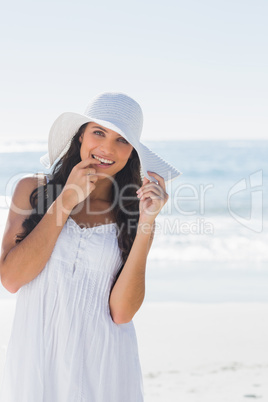 Beautiful brunette in white sunhat looking at camera