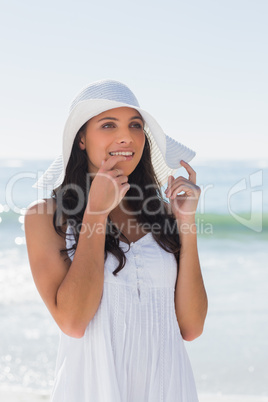 Pretty brunette in white sunhat looking away and touching hat