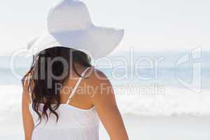 Pretty brunette in white sunhat looking at the ocean