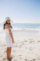 Brunette in white sunhat and dress looking over her shoulder at