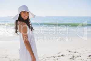Brunette in white sunhat looking over her shoulder at camera