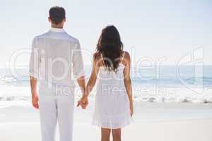 Attractive couple holding hands and watching the ocean