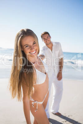 Blonde smiling at camera with boyfriend holding her hand