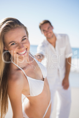 Blonde woman smiling at camera with boyfriend holding her hand