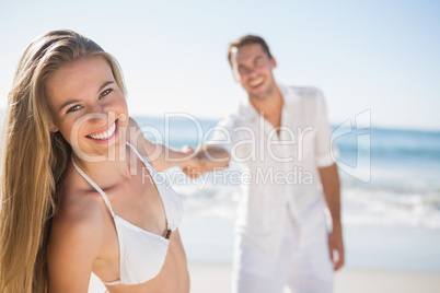Pretty woman smiling at camera with boyfriend holding her hand