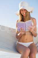 Happy blonde sitting on hammock reading book