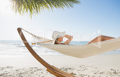 Woman wearing sunhat and bikini relaxing on hammock