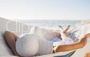 Peaceful woman in sunhat relaxing on hammock