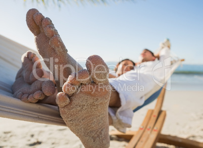 Close up of sandy feet of couple in a hammock