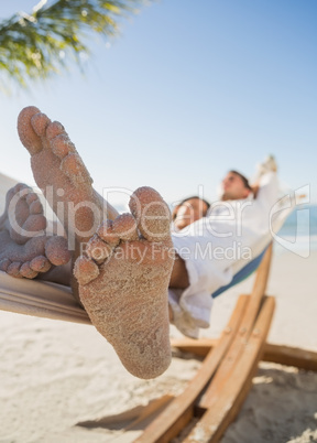 Close up of sandy feet of couple sleeping in a hammock