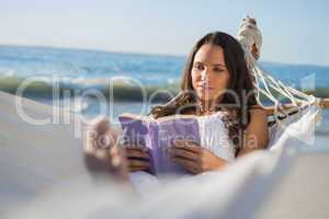 Content woman lying on hammock reading book