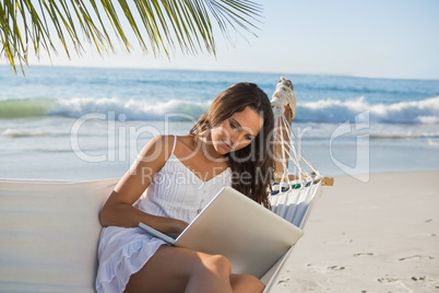 Pretty brunette sitting on hammock with laptop