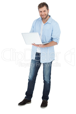 Smiling man using his laptop looking at camera