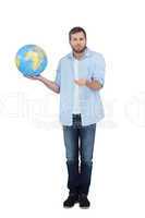 Charming model holding a globe and shrugging shoulders