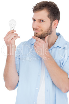 Sceptical model holding a bulb and looking at camera