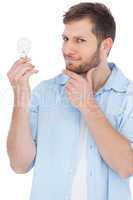 Sceptical model holding a bulb and looking at camera