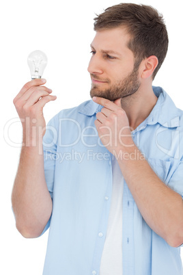 Sceptical model holding a bulb and touching his chin