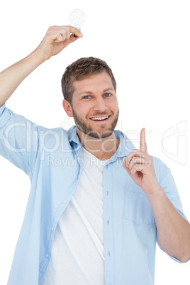 Smiling model holding a bulb above his head