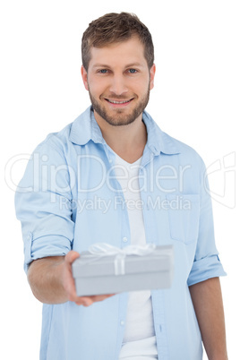 Happy man offering a gift looking at camera