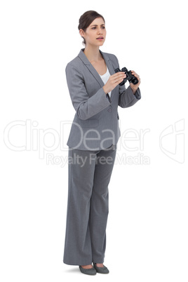 Curious young businesswoman with binoculars