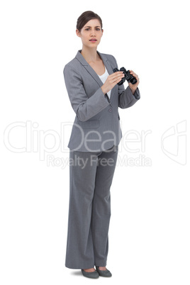 Curious young businesswoman posing with binoculars