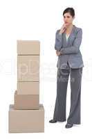 Thoughtful businesswoman posing with cardboard boxes