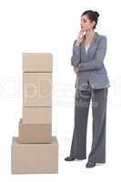 Thoughtful businesswoman with cardboard boxes