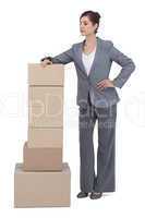 Confident businesswoman posing with cardboard boxes